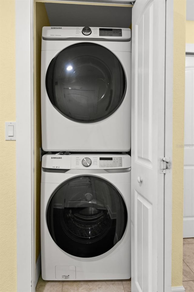 laundry area with light tile patterned floors and stacked washer / dryer