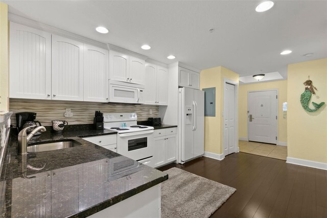 kitchen featuring white appliances, dark stone counters, white cabinets, sink, and decorative backsplash