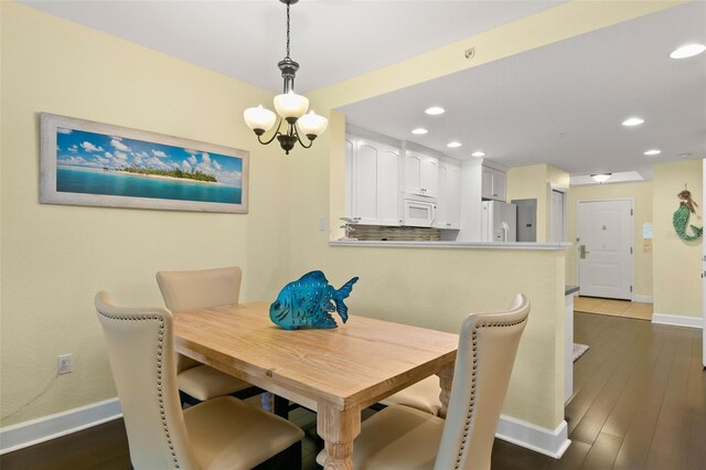 dining space with dark hardwood / wood-style floors and an inviting chandelier