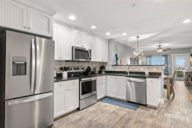 kitchen with stainless steel appliances, white cabinets, hanging light fixtures, and a peninsula