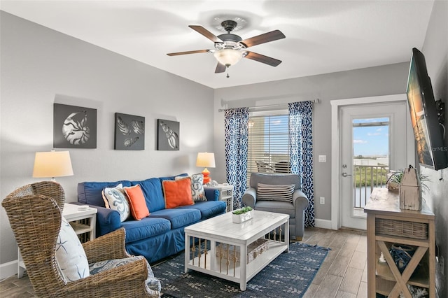 living area with baseboards, a ceiling fan, and wood finished floors