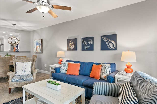 living area with ceiling fan with notable chandelier, wood finished floors, and baseboards