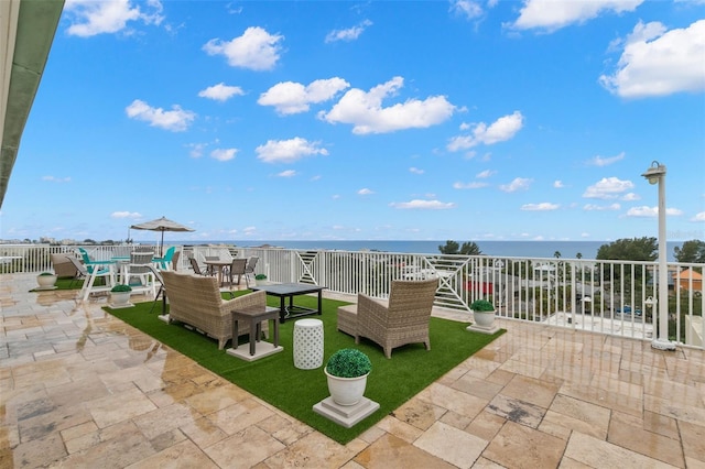 view of patio featuring a water view, fence, and outdoor dining space