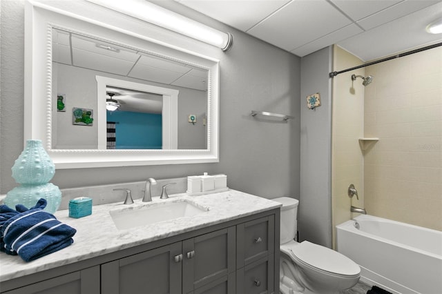 bathroom with a drop ceiling, toilet, vanity, and shower / tub combination