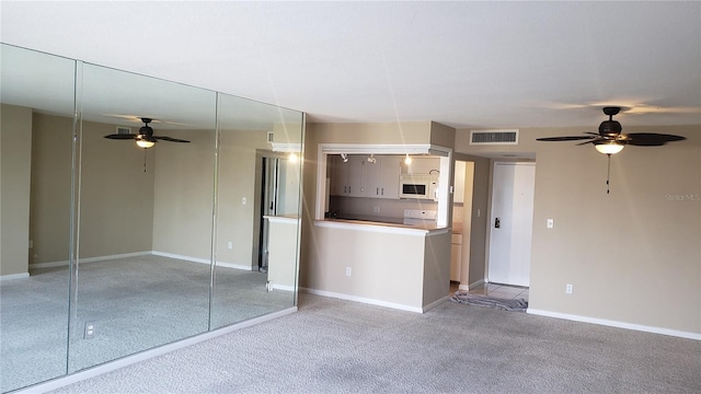 interior space featuring carpet, stove, and ceiling fan