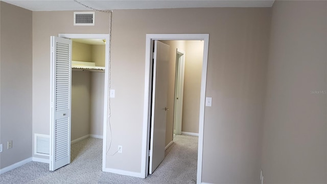 unfurnished bedroom featuring light carpet, a walk in closet, and a closet