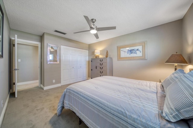 carpeted bedroom with ceiling fan, a textured ceiling, and a closet