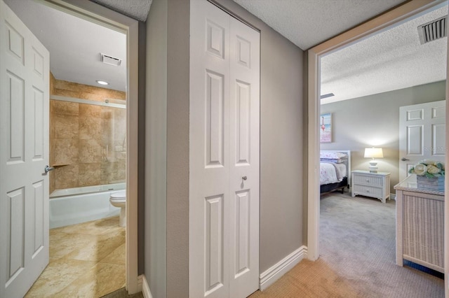 hallway with light carpet and a textured ceiling