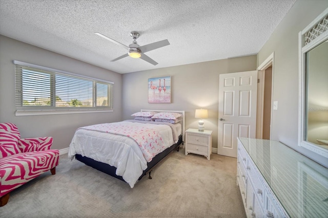 bedroom with ceiling fan, light carpet, and a textured ceiling