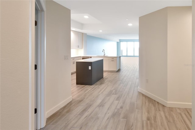 kitchen featuring a center island, sink, kitchen peninsula, light hardwood / wood-style floors, and white cabinets