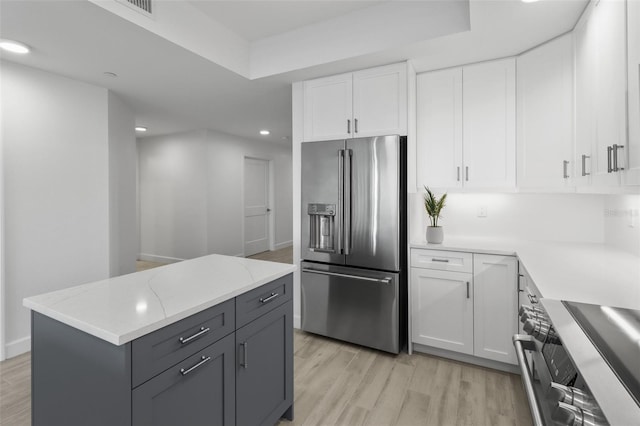 kitchen featuring light stone counters, stainless steel appliances, white cabinetry, light hardwood / wood-style floors, and a kitchen island