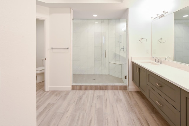 bathroom featuring an enclosed shower, vanity, toilet, and wood-type flooring