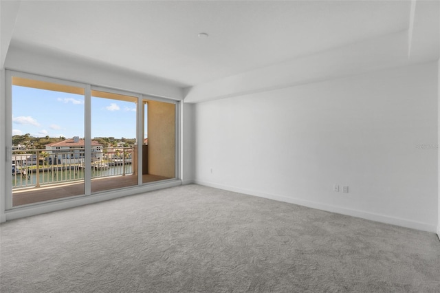 unfurnished room with carpet flooring and a water view