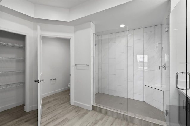 bathroom with hardwood / wood-style flooring, toilet, and walk in shower