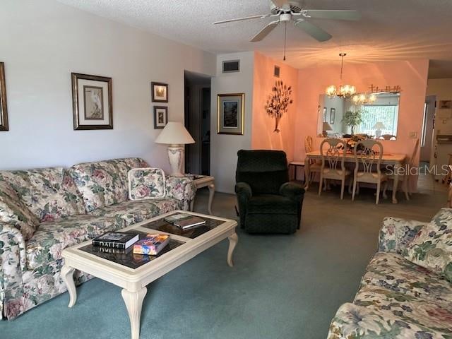 carpeted living room featuring a textured ceiling and ceiling fan with notable chandelier