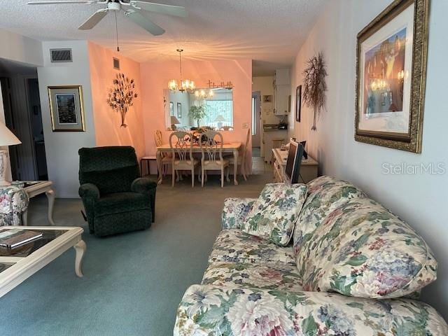 carpeted living room with a textured ceiling and ceiling fan with notable chandelier