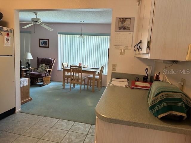 kitchen with pendant lighting, light tile floors, white fridge, ceiling fan, and a textured ceiling