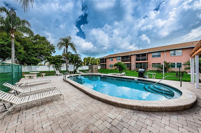 view of swimming pool featuring a lawn, a patio, and grilling area