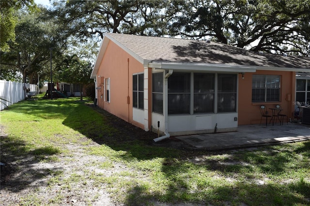 back of house with a sunroom, a lawn, and a patio