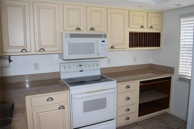 kitchen featuring cream cabinets, white appliances, and light tile patterned flooring