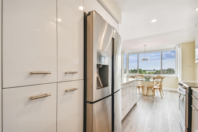 kitchen with hanging light fixtures, white cabinetry, a chandelier, light wood-type flooring, and stainless steel appliances