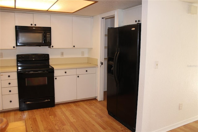 kitchen featuring white cabinetry, black appliances, and light wood-type flooring