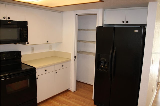 kitchen featuring white cabinets, light hardwood / wood-style floors, and black appliances