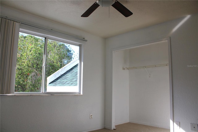 unfurnished bedroom featuring multiple windows, carpet, a closet, and ceiling fan