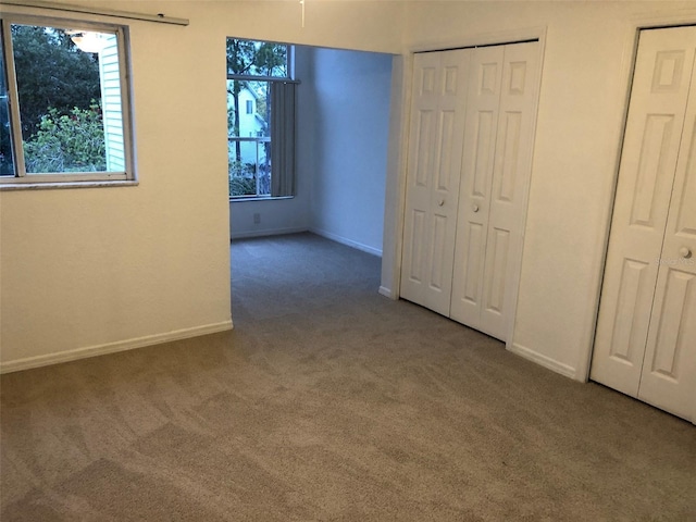 unfurnished bedroom with carpet floors and two closets