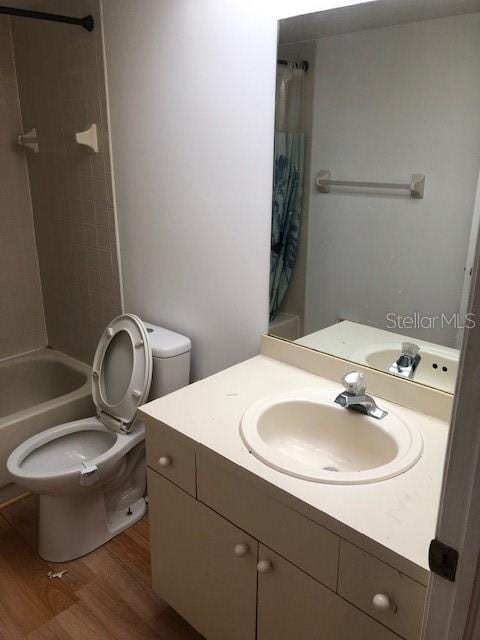 full bathroom with hardwood / wood-style floors, vanity, toilet, and shower / tub combo