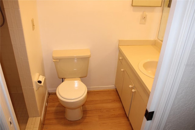 bathroom featuring a tile shower, hardwood / wood-style flooring, vanity, and toilet