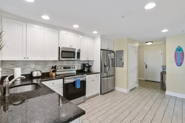 kitchen featuring appliances with stainless steel finishes, sink, backsplash, white cabinetry, and dark stone counters