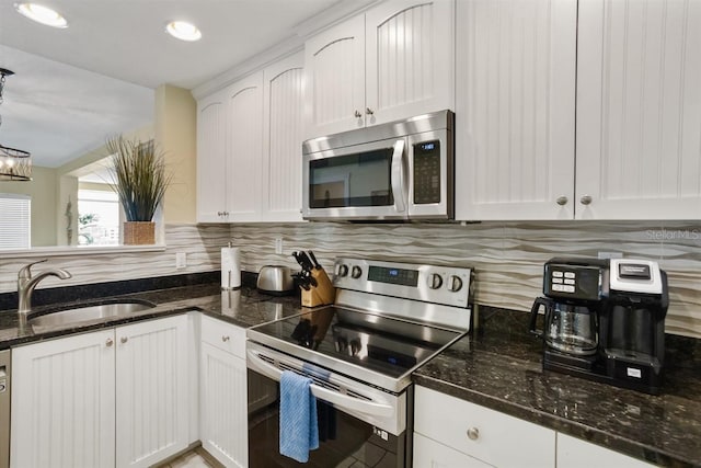 kitchen featuring sink, stainless steel appliances, hanging light fixtures, and white cabinets