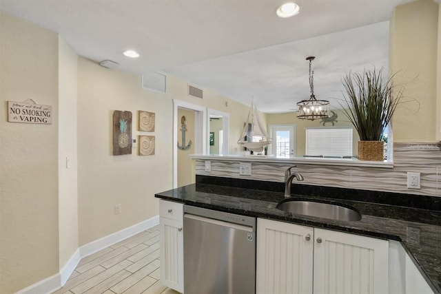 kitchen featuring sink, dishwasher, white cabinetry, and dark stone counters