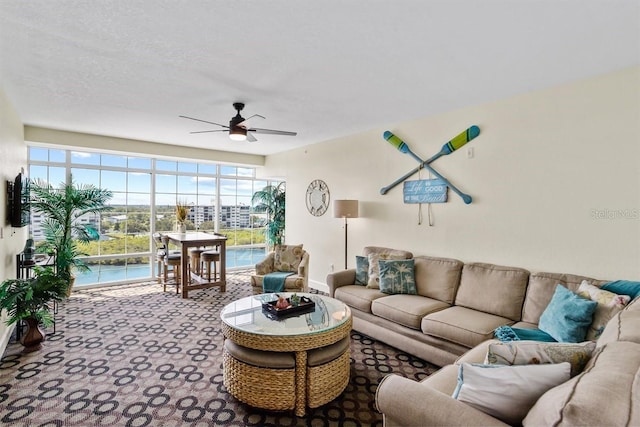 living room with ceiling fan, carpet flooring, and a textured ceiling