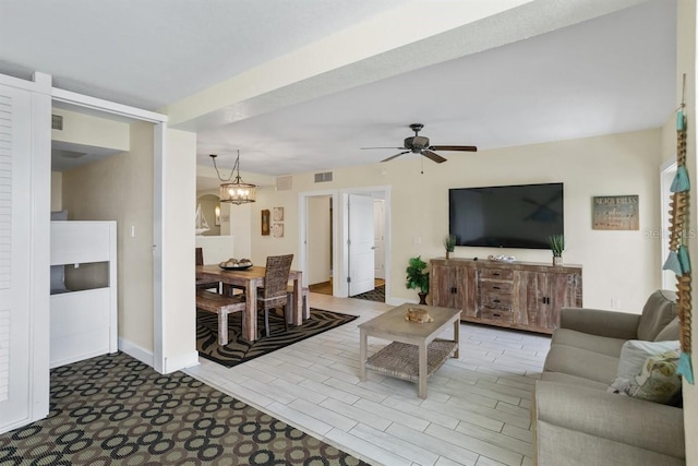 living room featuring ceiling fan with notable chandelier