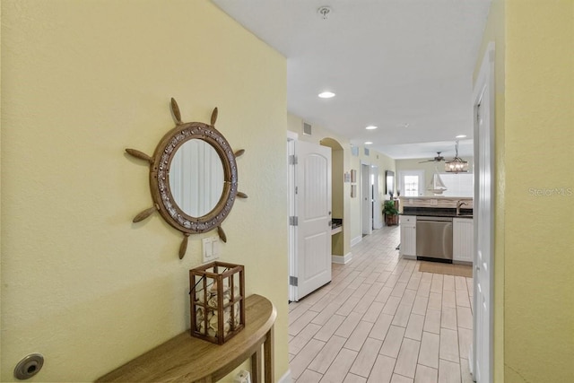 corridor with light hardwood / wood-style flooring and sink