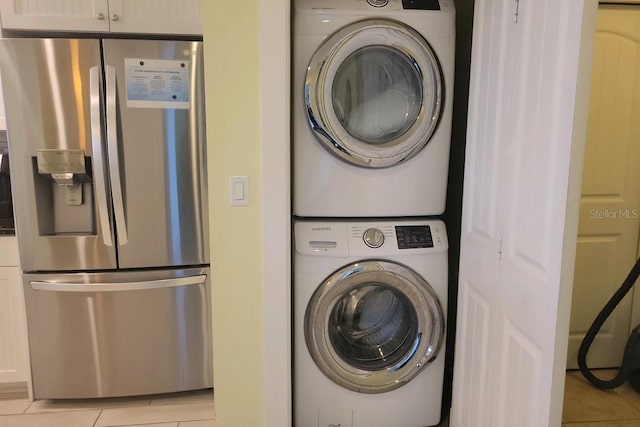 washroom featuring stacked washer and dryer and light tile patterned floors