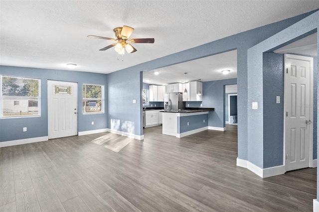 kitchen featuring white cabinetry, ceiling fan, dark wood-type flooring, stainless steel fridge, and a textured ceiling