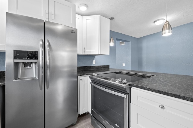 kitchen with dark stone countertops, white cabinetry, pendant lighting, and stainless steel appliances