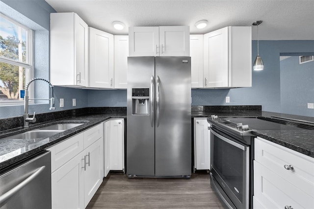 kitchen with sink, a textured ceiling, appliances with stainless steel finishes, decorative light fixtures, and white cabinetry