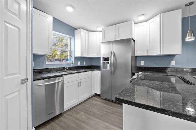 kitchen with decorative light fixtures, white cabinetry, sink, and appliances with stainless steel finishes