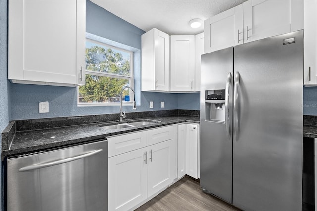 kitchen featuring sink, dark stone countertops, a textured ceiling, white cabinetry, and stainless steel appliances