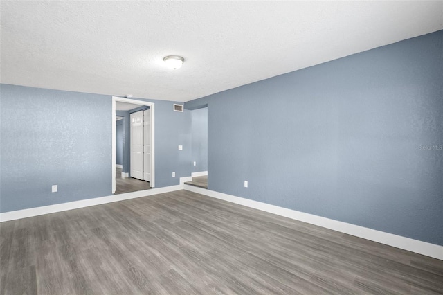 spare room featuring dark hardwood / wood-style flooring and a textured ceiling