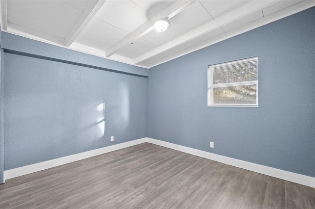 unfurnished room featuring hardwood / wood-style floors and vaulted ceiling with beams