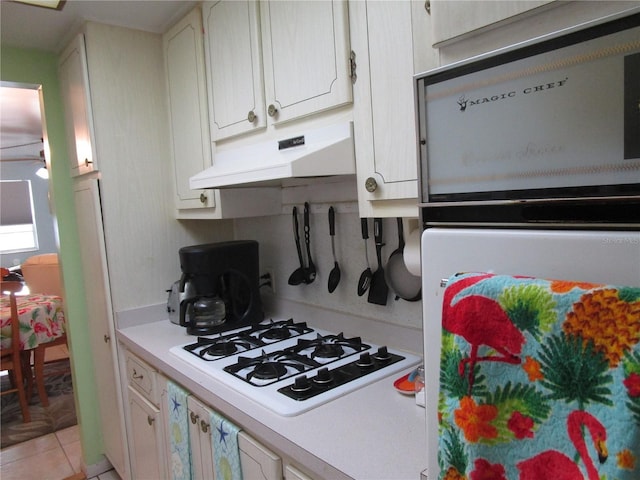 kitchen featuring white cabinets, white gas stovetop, and light tile patterned floors