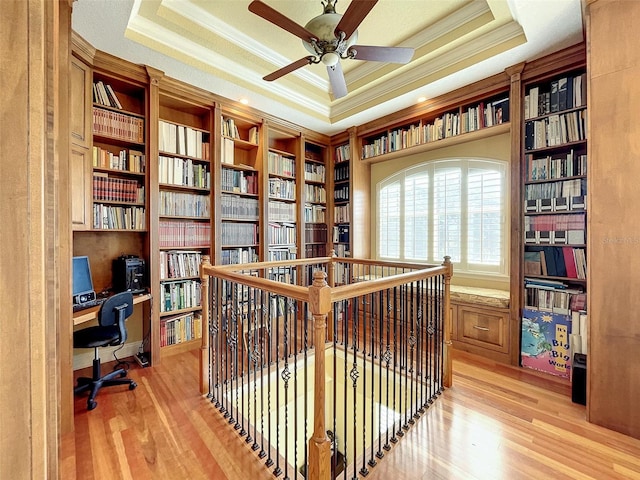 office featuring a raised ceiling, light wood-type flooring, and built in study area