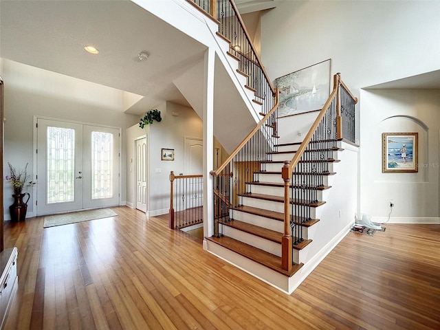 foyer featuring french doors, baseboards, a high ceiling, and wood finished floors