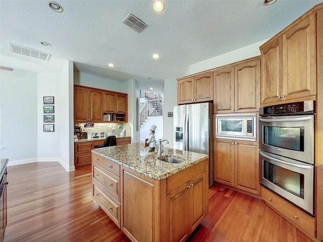 kitchen featuring visible vents, appliances with stainless steel finishes, a sink, and light stone countertops