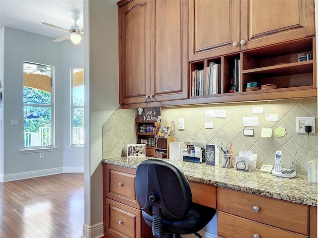 office space featuring baseboards, wood finished floors, a ceiling fan, and built in study area